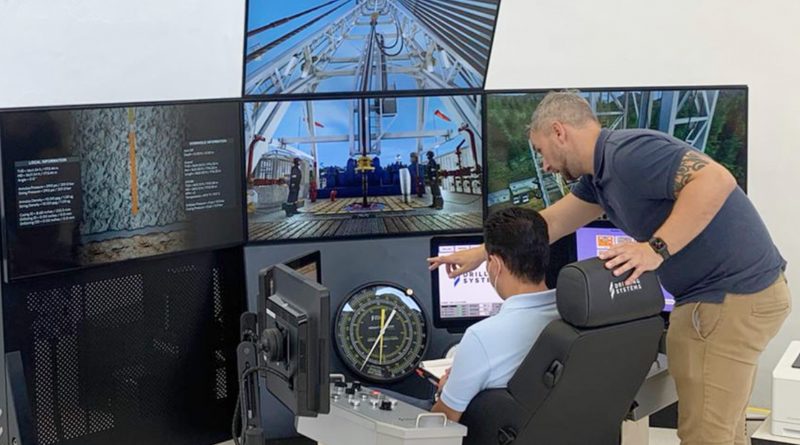 Two men in a control room monitor multiple screens displaying drilling operations. One seated man operates controls while another man stands beside him, pointing to a screen.