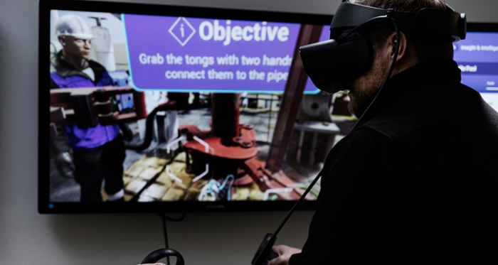 A person wearing a VR headset interacts with a virtual environment displayed on a screen, showing an instruction to 