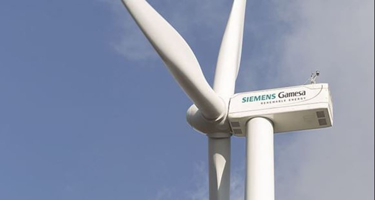 Close-up of a Siemens Gamesa wind turbine with three blades against a clear blue sky.