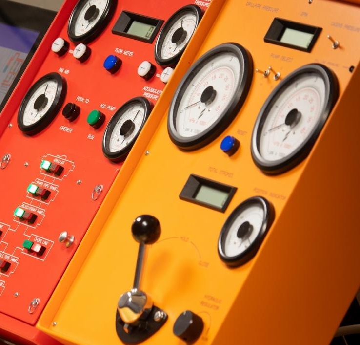 Close-up of two control panels, one red and one yellow, featuring various dials, switches, buttons, and gauges, indicating instrumentation for machinery or technical equipment.