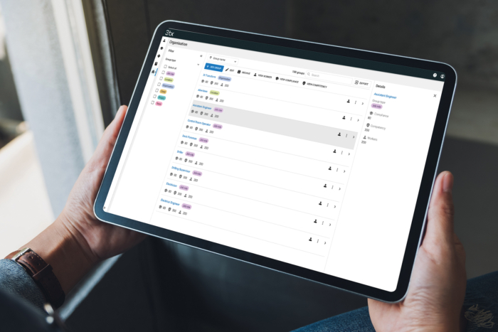 Person holding a tablet displaying a task management application with a list of tasks and their statuses.