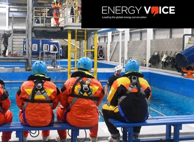 Three people in protective gear and helmets seated on a bench near a training pool in an industrial facility, with 