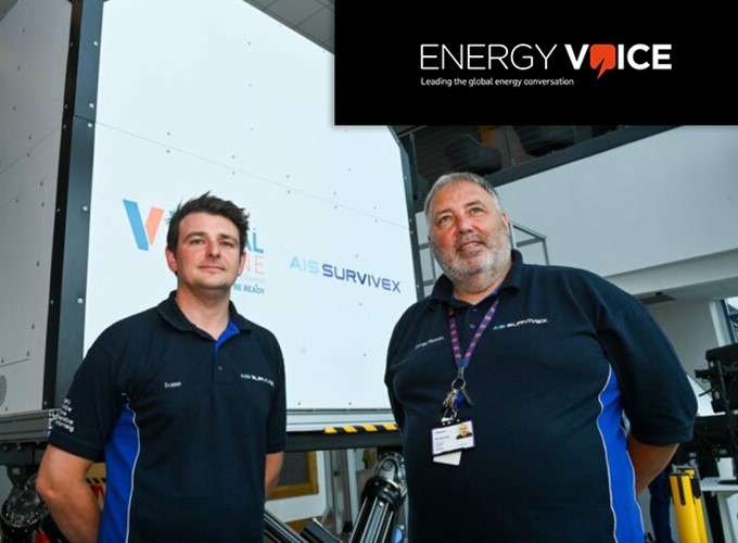 Two men in branded shirts stand in front of industrial equipment. The logo 