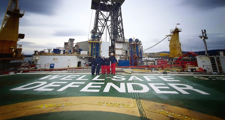 Four people in work uniforms stand on the deck of the offshore drilling rig 