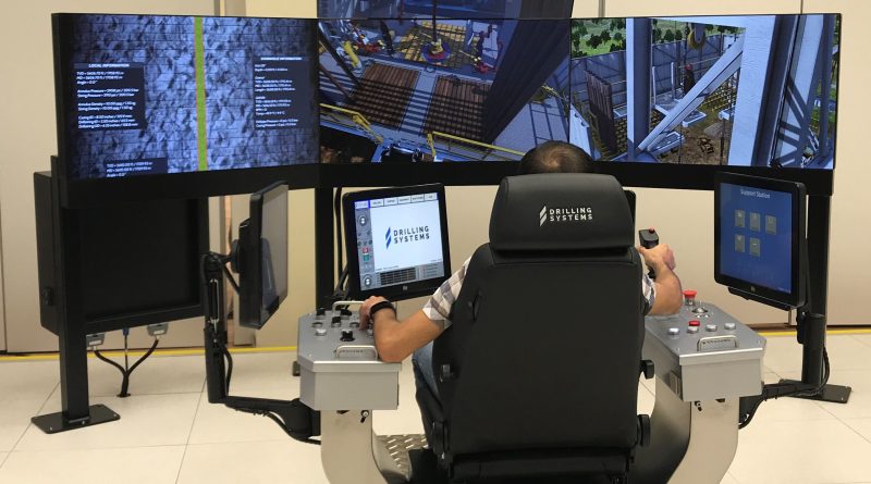 Person operating a drilling simulator with multiple screens and control panels.