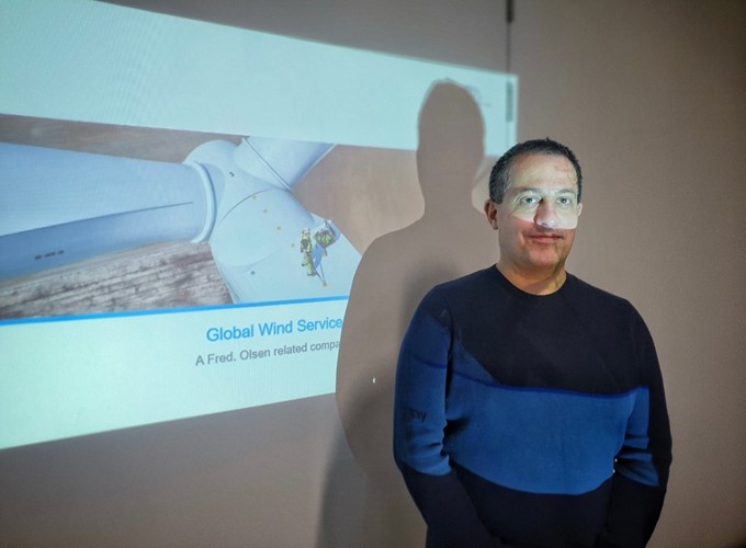 A person stands in front of a projection screen displaying 