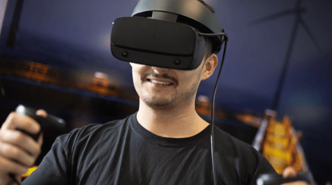 A man wearing a virtual reality headset and holding controllers in both hands.