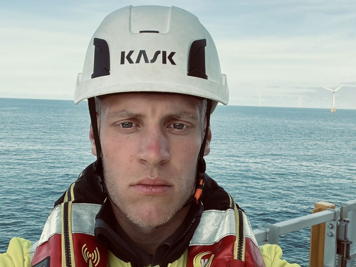 selfie de un hombre en alta mar con turbinas eólicas