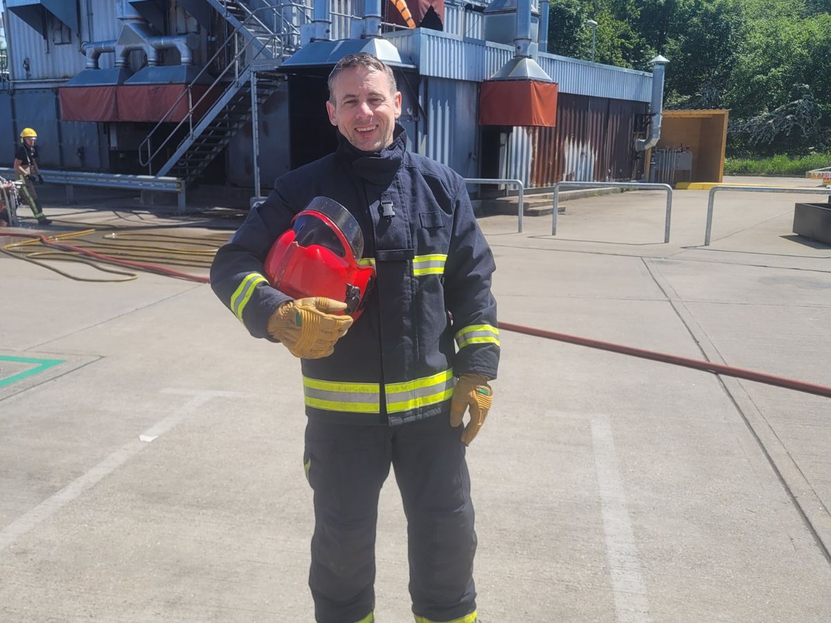 firefighter holding helmet in front of helideck fire training ground