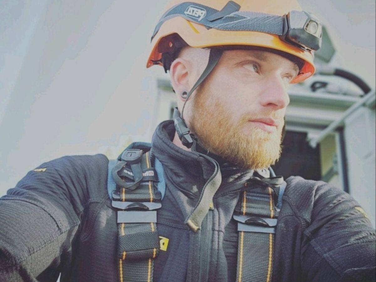 wind technician with an orange helmet and safety gear on.