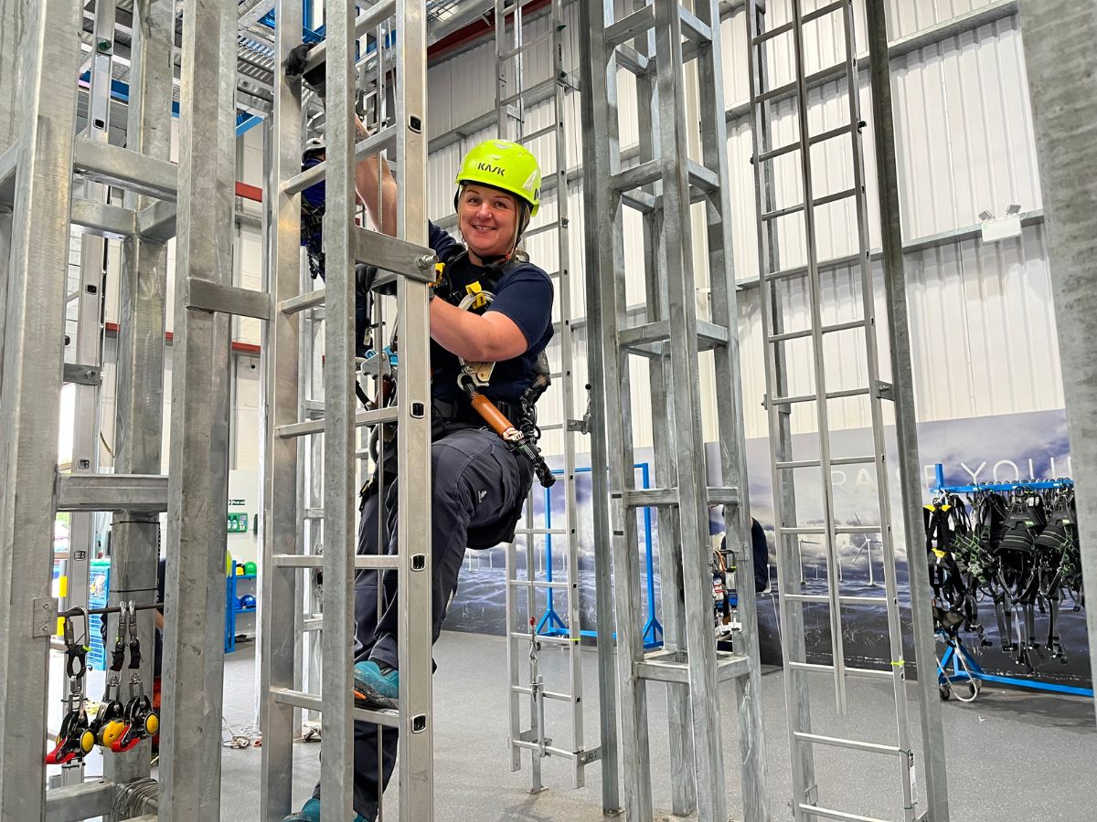 3t instructor con un casco de neón subiendo una escalera para la formación GWO.