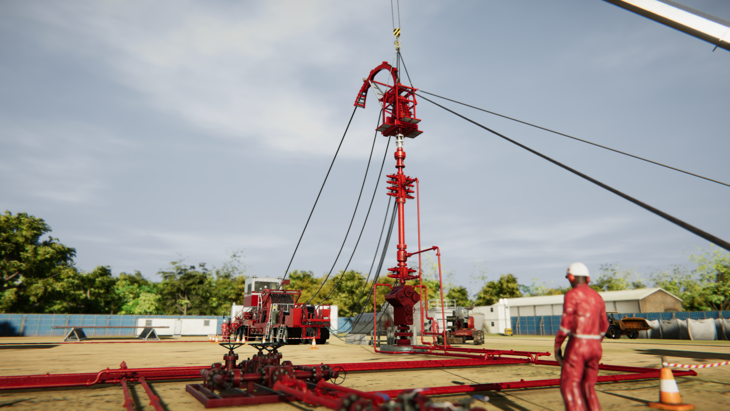 An oil drilling setup with red machinery and cranes is bustling with activity. A worker in red protective gear and a helmet stands nearby, perhaps undergoing training. Trees and buildings form the backdrop to this industrious scene.