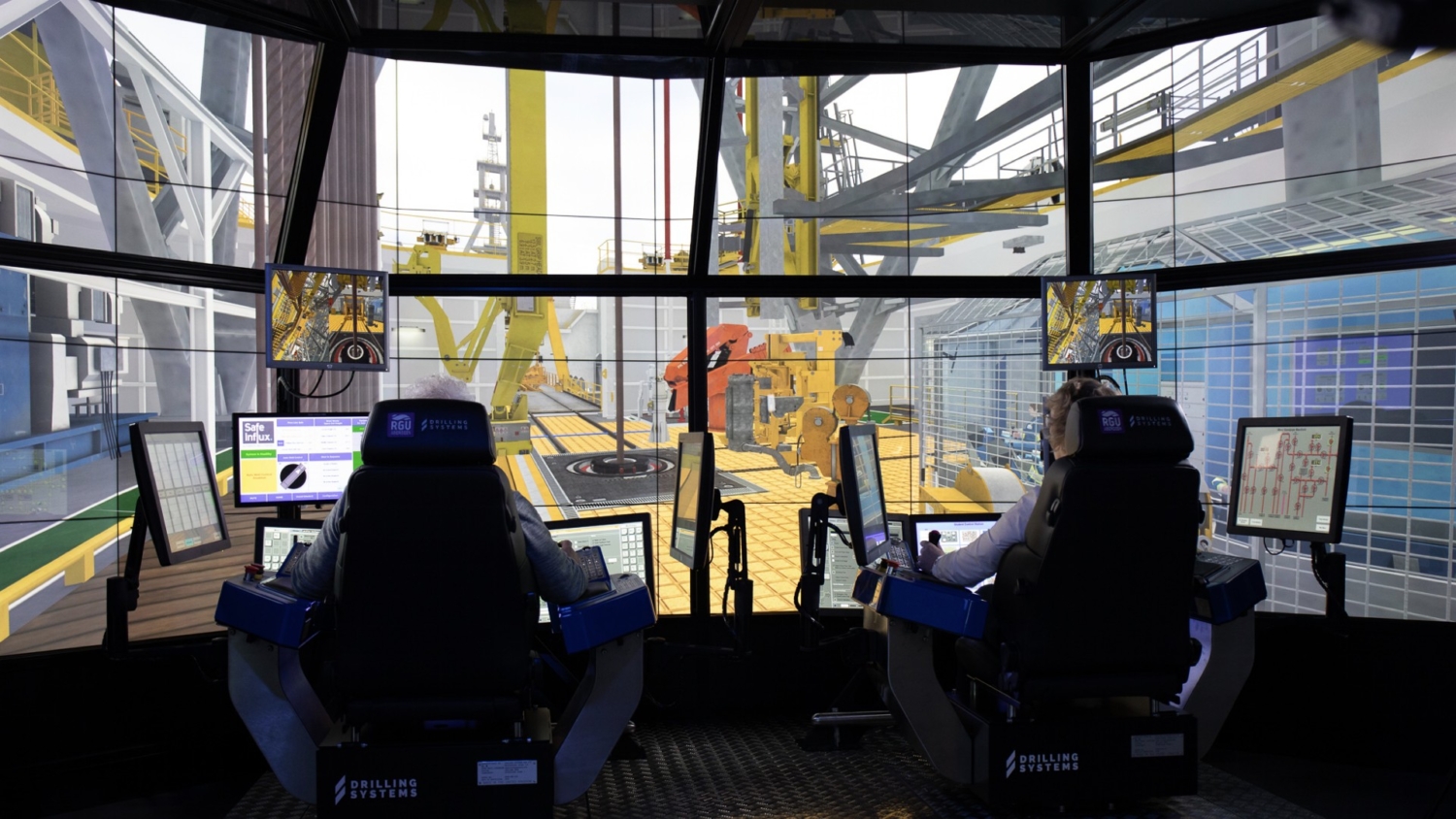 Two people engage in a simulated offshore drilling control room, utilizing multiple screens and realistic visuals of equipment to enhance their training experience.