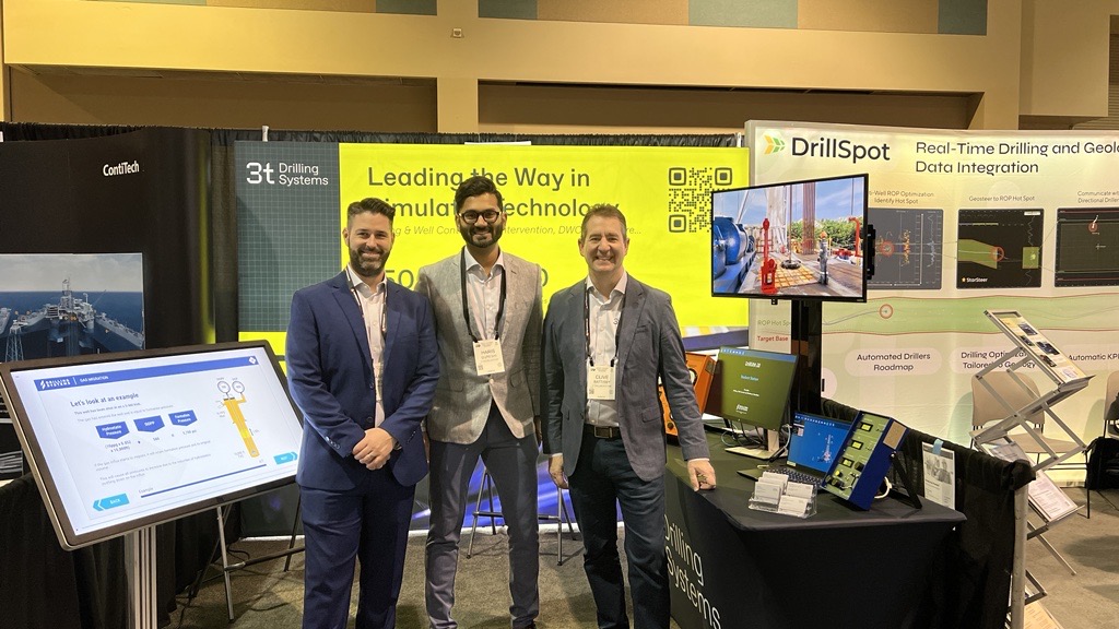 Three men in suits stand in front of an exhibition booth featuring cutting-edge technology displays and promotional banners, emphasizing innovative training solutions.