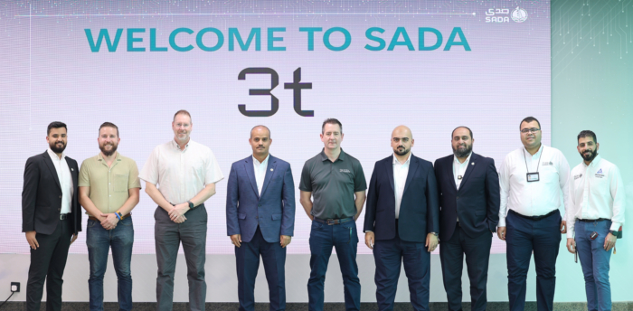 A group of eight men stands proudly in front of a sign that says 