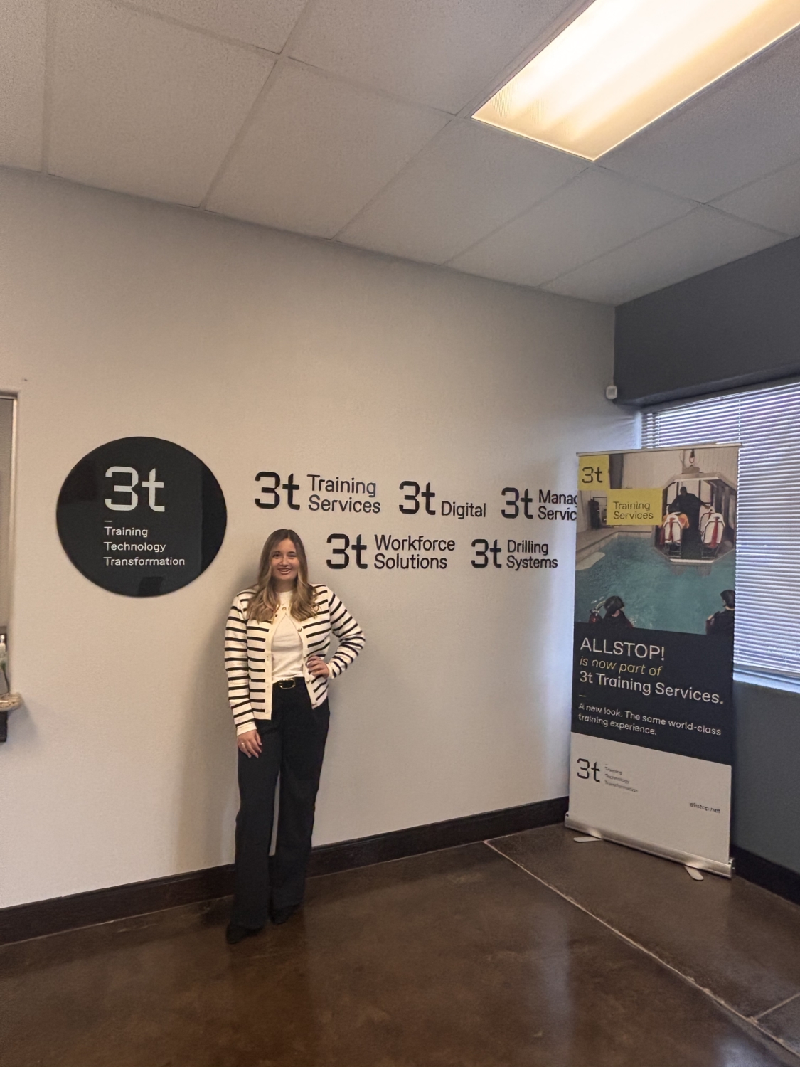 Bid writer Danielle standing against a wall with 3t branding